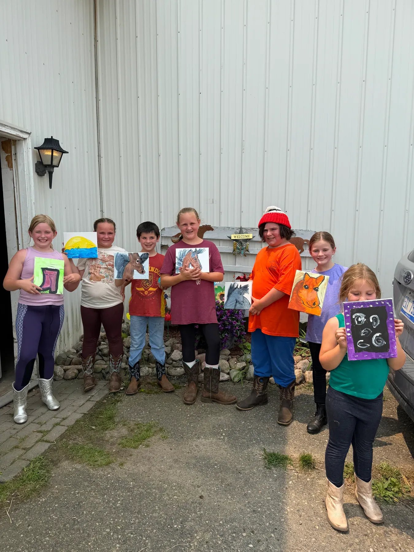 Campers smiling and displaying their horse-themed paintings