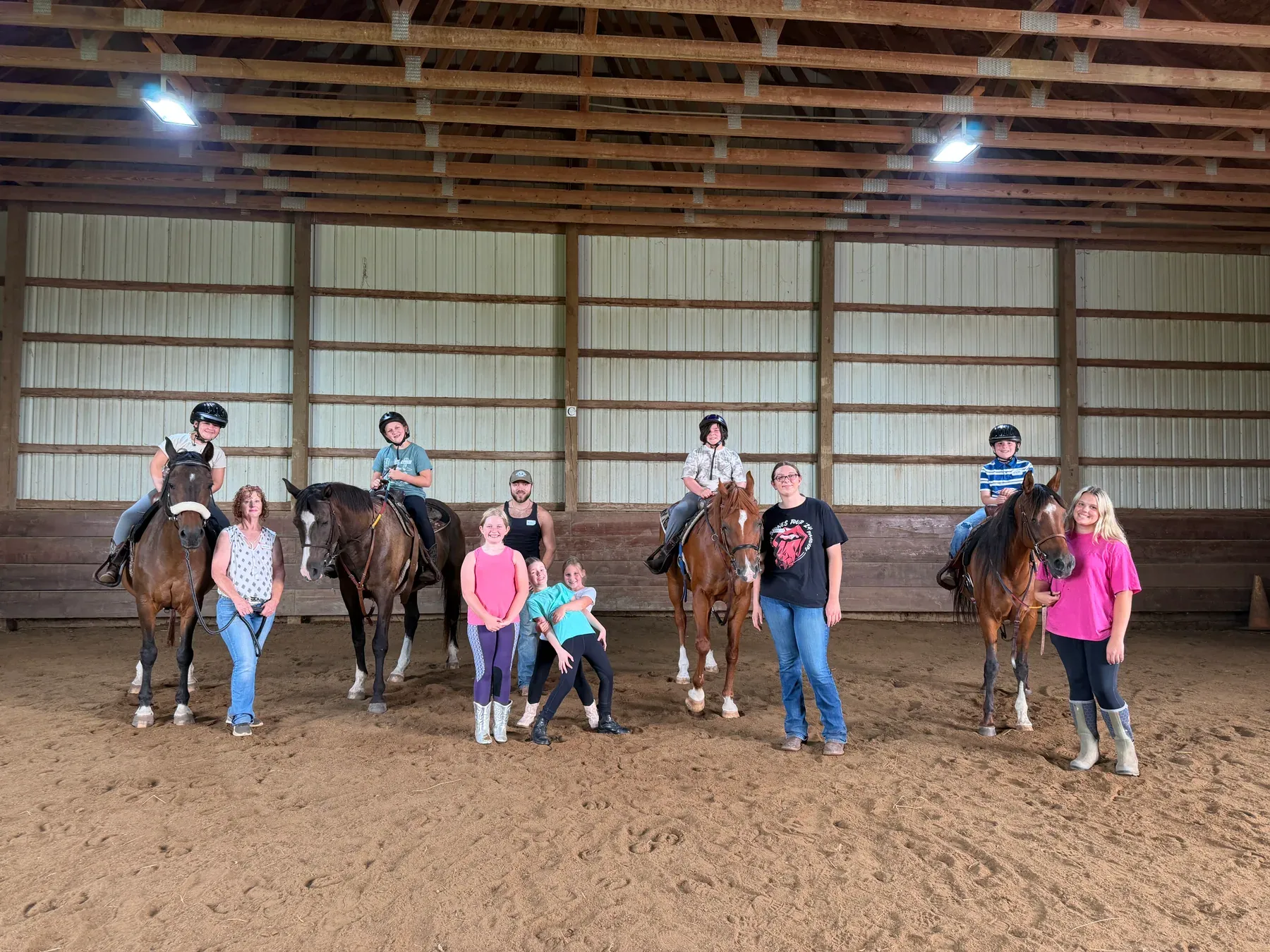 Campers, instructors, and four horses gathered in the indoor arena at MSB Riding Academy